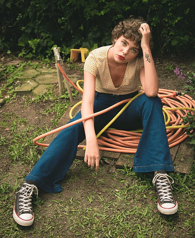 Girl tangled up in a garden hose looking frustrated