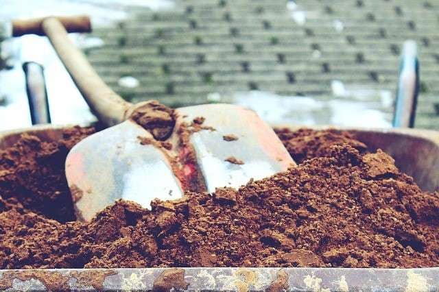 closeup of a wheelbarrow full of soil and a shovel