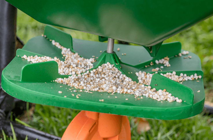 closeup of fertilizer granules in a spreader's tray